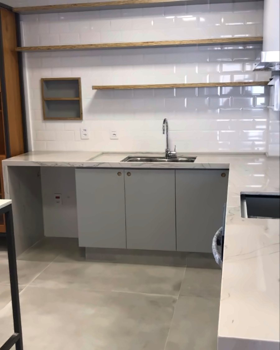 Cozinha branca com bancada em porcelanato, prateleiras suspensas e nicho embutido