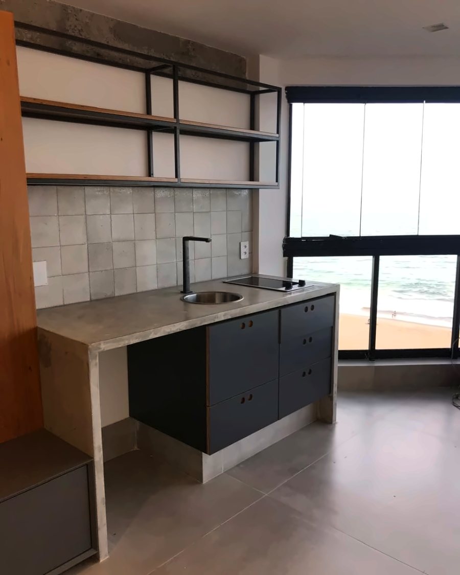 Cozinha com bancada de concreto, prateleiras metálicas aparentes e armário grafite