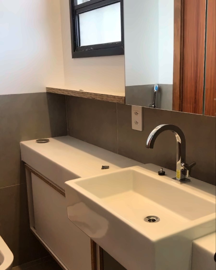 Lavabo com cuba esculpida sobre marcenaria sob medida e revestimento cimentício